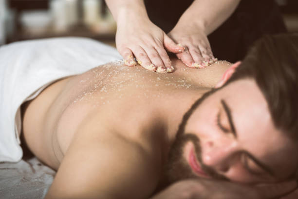 Man at beautician's getting an exfoliating massage with salt peeling